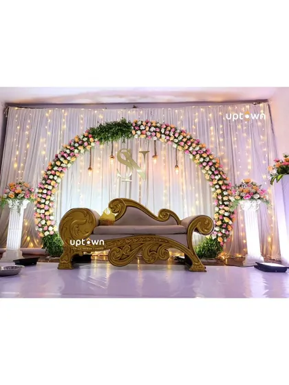 An elegant engagement stage with a floral arch and fairy lights.
