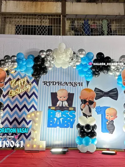 A fun Boss Baby theme for Ridhan's first birthday. This outdoor setup uses a blue, black, and white color scheme with a balloon arch and character cutouts.