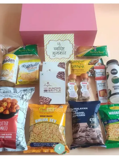An unboxed view of the room hamper for wedding guests. It's packed with an assortment of treats like Bhujia Sev, Butter Tomato makhana, Badam drink, and coconut water to make their stay delightful.