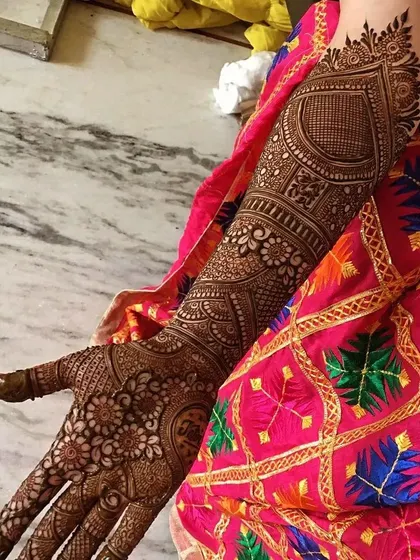 A stunning single-arm view of a full bridal design. The large heart shape is filled with fine-line work, surrounded by traditional patterns that extend up the arm.
