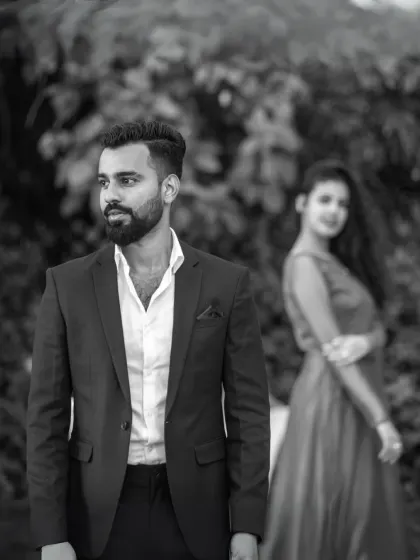 A classic black and white portrait that emphasizes emotion. The focus on the groom with the bride softly in the background creates a thoughtful and artistic composition.