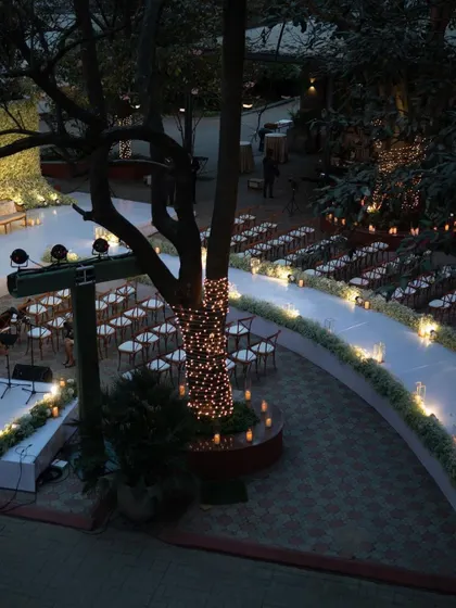 The outdoor lounge area for a reception, illuminated by fairy lights and candles. The elegant white furniture and surrounding greenery created a cozy and romantic space for guests to relax.
