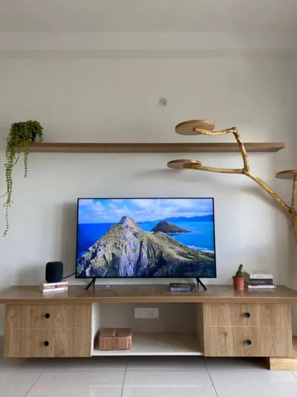 This entertainment corner is next-level chill. Loving the clean, natural vibes with that wood finish and a unique, tree-like cat-friendly shelf.