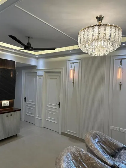 This living area showcases our expertise in creating dramatic lighting and wall textures. A grand crystal chandelier serves as the centerpiece, complemented by vertical fluted panels and elegant wall sconces. The design creates a sense of height and luxury.