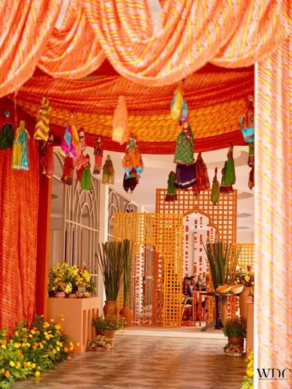 Another view of the entrance, showing how the 'lehariya' drapes and hanging puppets lead into a space filled with jali panels and more traditional decor elements, creating an immersive experience.
