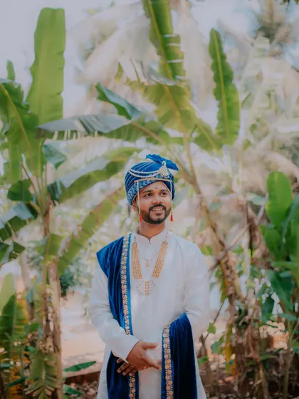 A smiling portrait of the groom against a backdrop of lush palm trees.