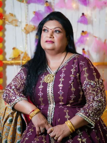 A pretty and dramatic look for a festive event. The makeup is glamorous, with a focus on the eyes, and complements her embroidered purple outfit.