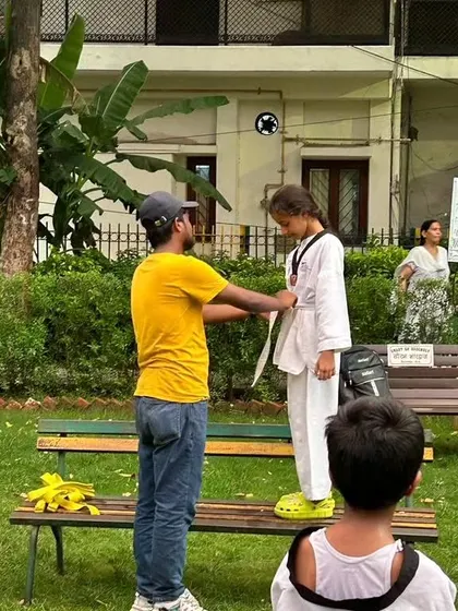 Carefully tying the new belt for a student. This is a significant moment in their Taekwondo journey.