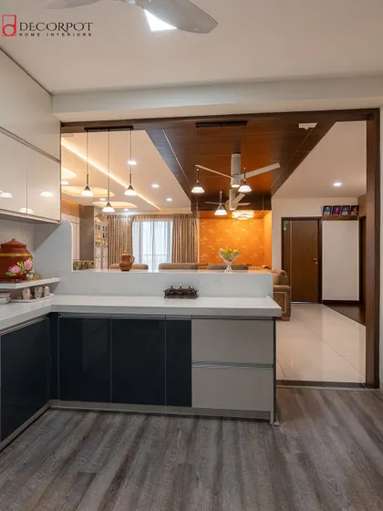 A view from the kitchen into the living room, showing how an open layout with a breakfast bar can create a connected and social home environment. The wood and dark laminate combination adds a touch of modern elegance.