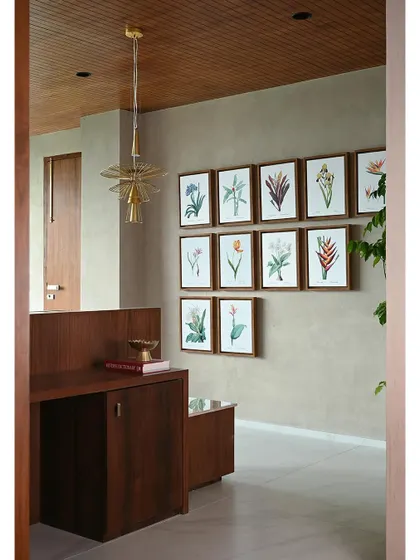 The entrance to the executive suite, where a gallery wall of botanical prints and a sculptural brass light fixture set a tone of refined elegance. The warm wood tones create a welcoming first impression.
