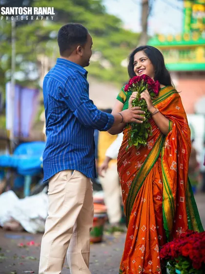 A romantic gesture captured as the groom presents a bouquet of roses to his bride-to-be in a market setting.