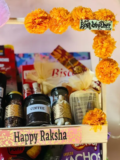 The festive marigold decorations on this Rakhi hamper add a traditional and cheerful touch.