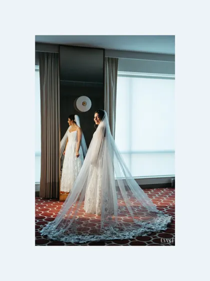 A stunning shot of the bride looking in the mirror, her long, intricate veil spread out behind her. A picture of pure bridal elegance.