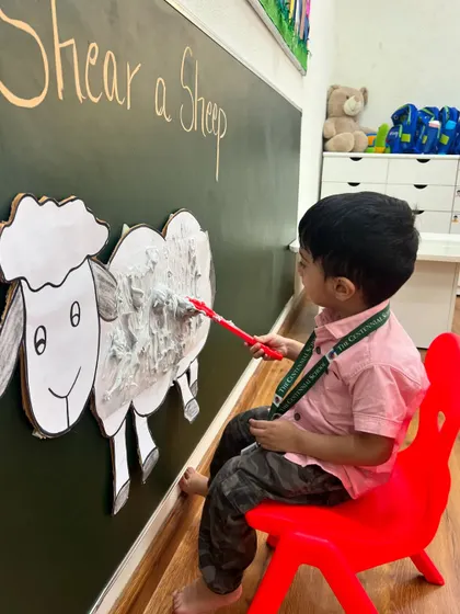With great concentration, a student helps get the sheep ready for warmer weather. This role-playing activity helps children understand the relationship between humans and animals.