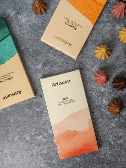 A minimalist flat lay of Artisanté chocolate bars. The clean composition and textured background create a modern, sophisticated look that highlights the elegant packaging design.