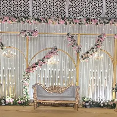 The same romantic stage setup, now with a vintage-style sofa. The combination of the intricate sofa, floral arches, and warm lighting creates a fairytale-like setting.
