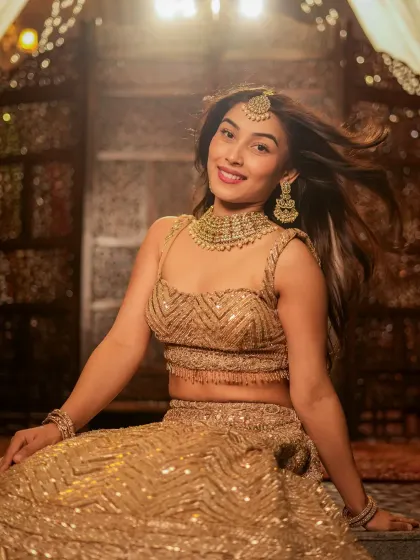 A smiling, candid-style shot from the golden lehenga series, showing the model's personality.
