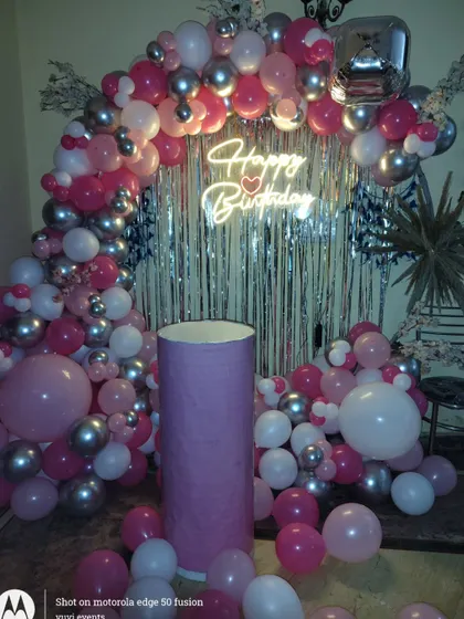 Another view of the pink and silver balloon arch against a silver fringe curtain.