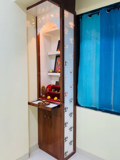 The doors of this bedroom mandir feature a lotus jaali pattern, and a pull-out tray provides extra space for placing offerings.
