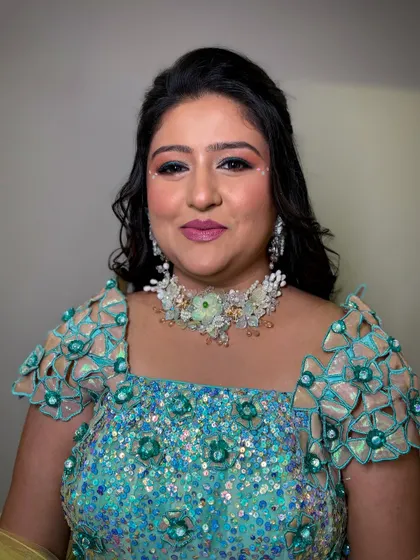 A portrait of the client, her makeup looking fresh and vibrant against the green background.