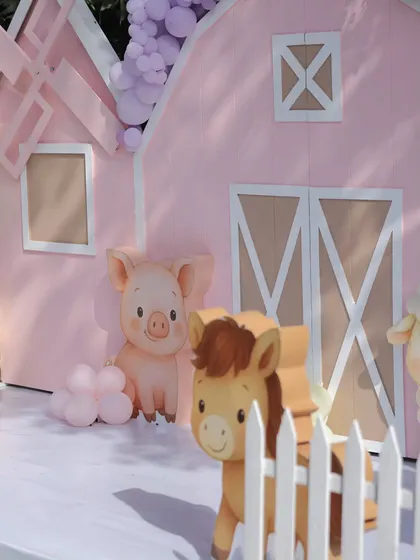 A detail shot of the pink barn backdrop, featuring a cute pig and horse. The clean lines and pastel colors are part of our signature stylized approach to classic children's party themes.