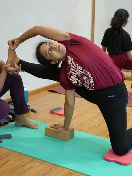 A glimpse from a recent session, where I provide hands-on adjustment to help a student safely deepen her hip-opening stretch using a block for support.