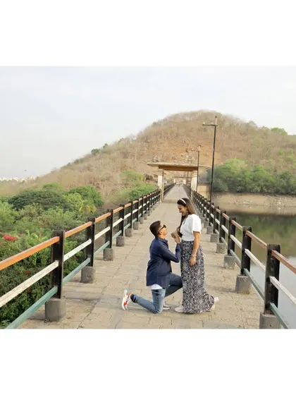 A beautiful proposal moment on a bridge over a lake, as the groom gets down on one knee for his bride-to-be.