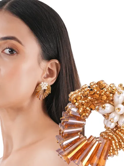 The Ninaara Gold Studs, with their open-hoop design and pearl flower centre, are a modern take on classic gold earrings.