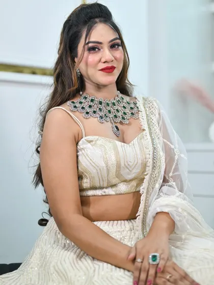 A close-up portrait showing an alternative jewellery pairing with the ivory lehenga. This features a stunning emerald and American diamond necklace.