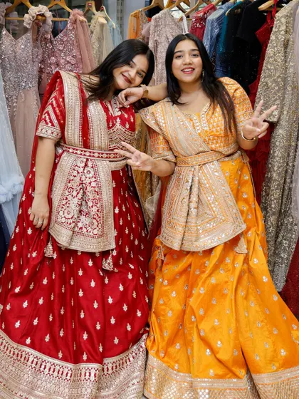 A fun pose from two friends in their bright and bold rental lehengas, showing the joy of dressing up together.