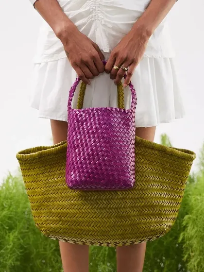 Big and small, our handwoven bags come in all sizes. Here, the vibrant purple Axel Mini is held against the olive green Axel Large, showcasing the range of colors and sizes in our Summer '24 collection.