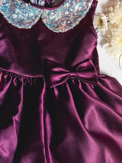 Dazzling in rich wine-colored satin, this dress is perfect for holiday parties and formal events. The standout feature is the sparkling sequin Peter Pan collar that adds a touch of festive shimmer.