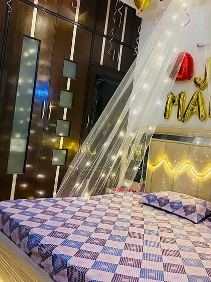 A side view of the 'Just Married' room decor, showing how the fairy light canopy drapes elegantly next to the bed and wardrobe.