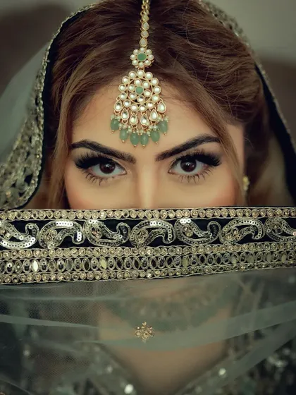 An intense and beautiful close-up of a bride's eyes. Peeking over her veil, this shot captures the mystery and anticipation, drawing focus to her expressive gaze and intricate makeup.