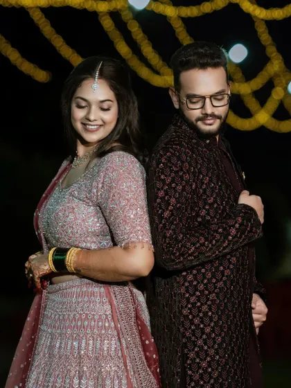 A playful back-to-back pose. This shows the full reception attire for both the bride and groom.