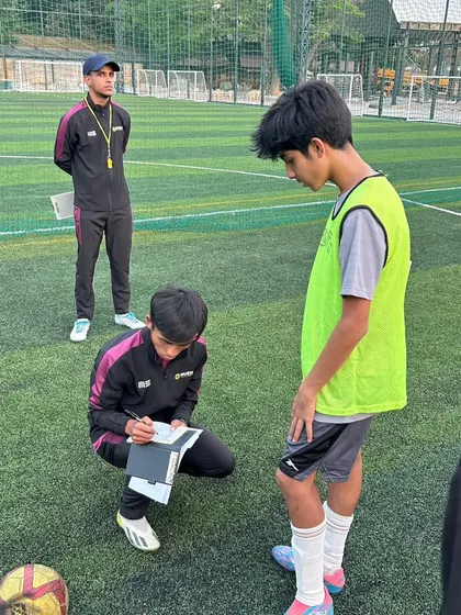 A coach takes notes while observing a player. This one-on-one attention is crucial for personalized feedback and creating tailored development plans.
