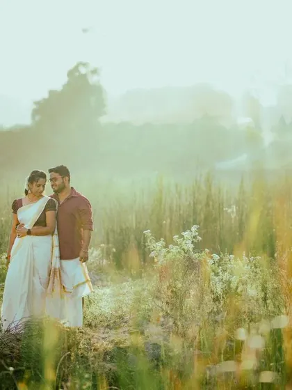 A dreamy, sun-drenched pre-wedding photo in a field. The hazy light creates a soft and romantic atmosphere.