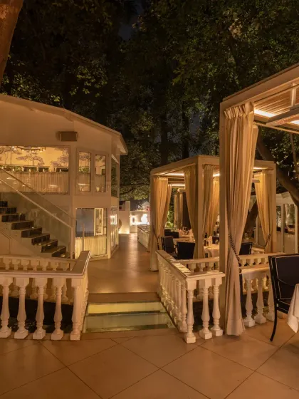 An evening view of our multi-level outdoor dining area. The combination of private cabanas and the elegant main building creates a unique and enchanting atmosphere.