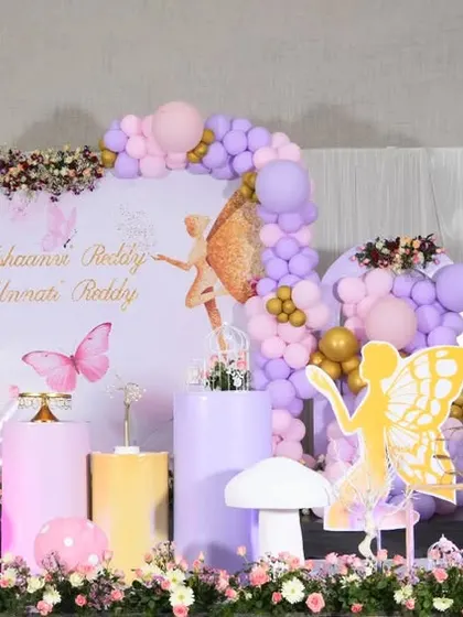 A wide view of our fairy garden theme, perfect for a large venue. The setup includes large fairy wing cutouts, floral arrangements, and a soft pastel color scheme.