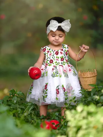 A little princess searching for the perfect apple. Dressed in a beautiful floral gown, she explores the garden with her basket in this enchanting themed photoshoot.