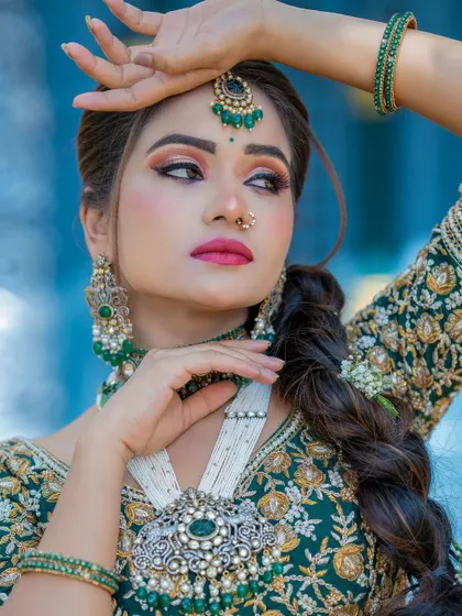A close-up portrait showcasing the detailed eye makeup and contouring for this bridal look. The combination of the green outfit and silver jewelry creates a striking contrast.
