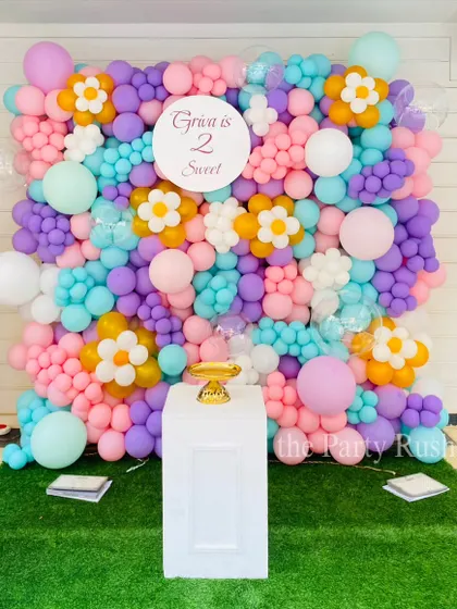 This 'Two Sweet' party theme features a stunning balloon wall in a pastel floral design. It's a beautiful and modern take on a backdrop that provides a fantastic photo opportunity for the birthday girl and her guests.