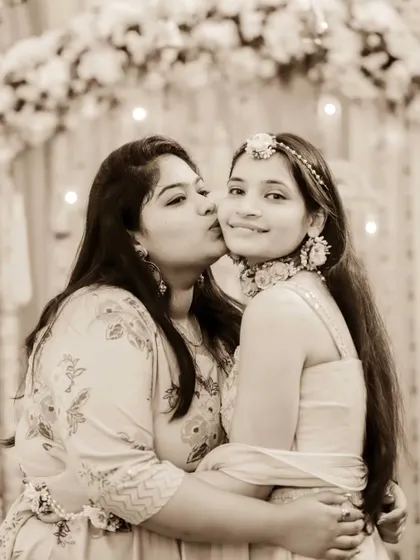 A tender moment between sisters at the Haldi ceremony. A sweet kiss on the cheek shows their love and excitement for the bride.
