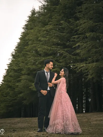 A beautiful shot of the couple standing in a forest clearing, her pink gown providing a stunning pop of color against the tall green trees.