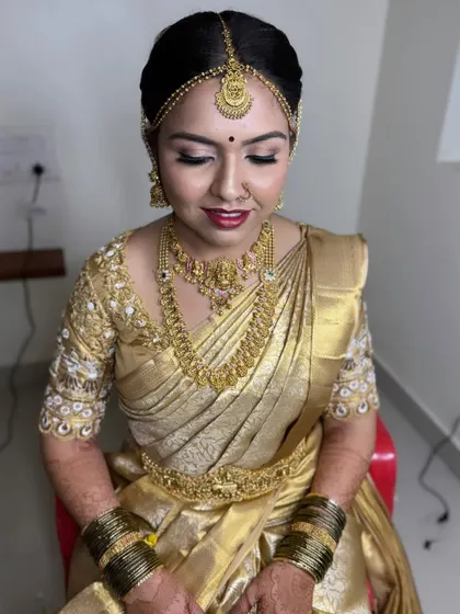 A full shot showing the elegant posture and the flawless draping of the silk saree. The makeup is kept subtle and glowing to match the all-gold theme.