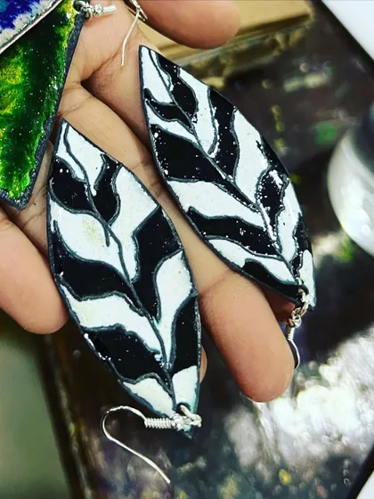 A close-up of the handcrafted enamel earrings, showing the glossy finish and the handmade silver hooks.