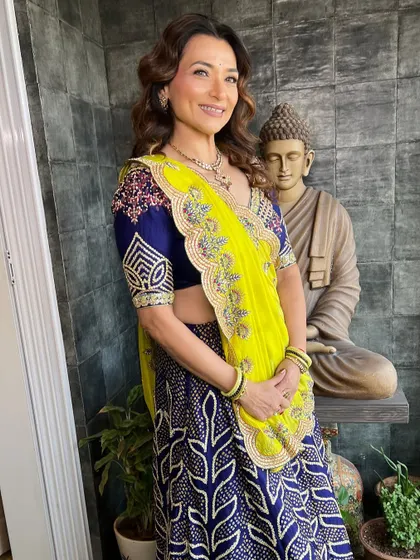A full-length photo showcasing her complete look. The makeup complements her vibrant outfit perfectly.