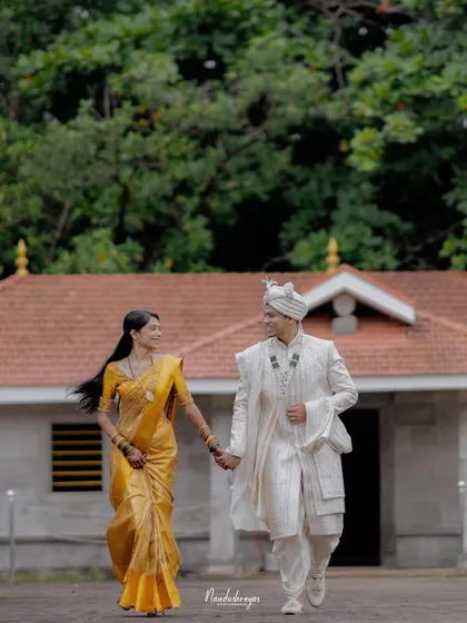 A couple walks hand-in-hand away from a traditional building towards the viewer, a beautiful motion shot from their riverside session.