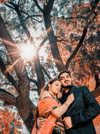A sun-kissed embrace under a sprawling tree, with the heritage architecture in the background. This shot perfectly blends nature with royal history.