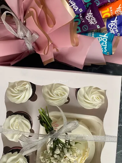 A top-down view of the sweet and savory hamper, showing the neatly arranged cupcakes and the colorful bouquet of protein bars.